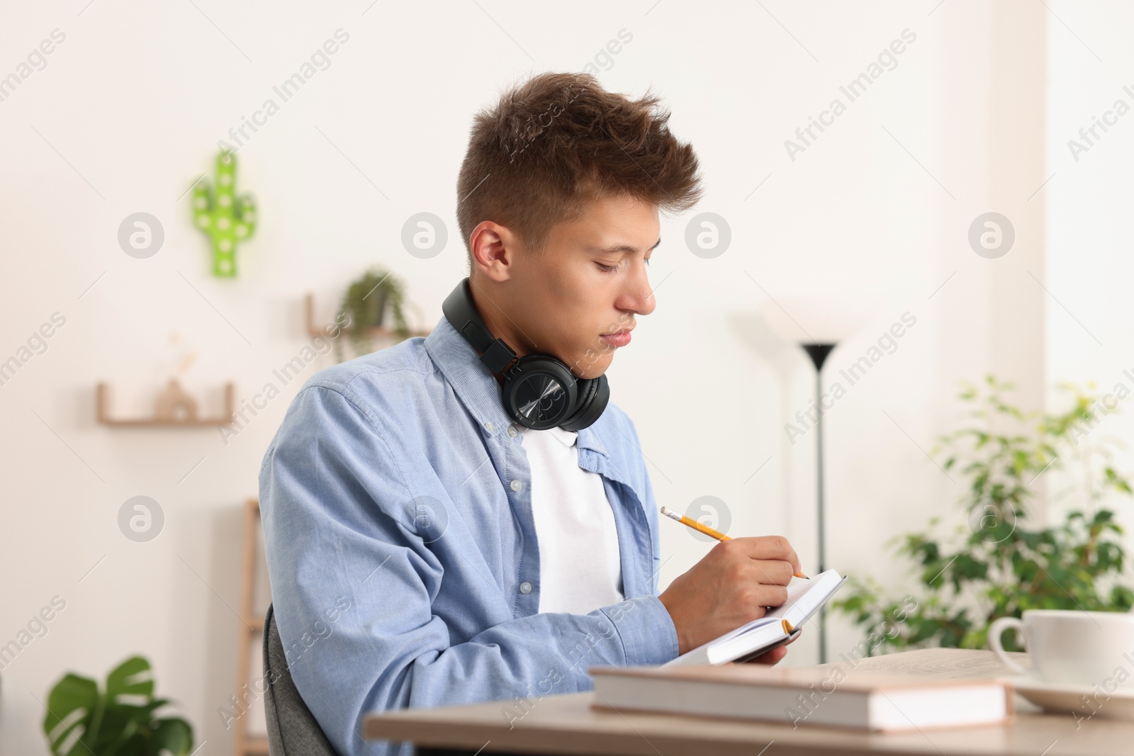 Photo of Student with headphones studying at table indoors