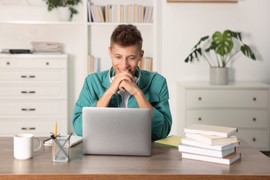 Photo of Student studying with laptop at table indoors