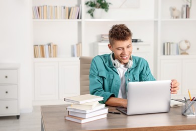 Student studying with laptop at table indoors