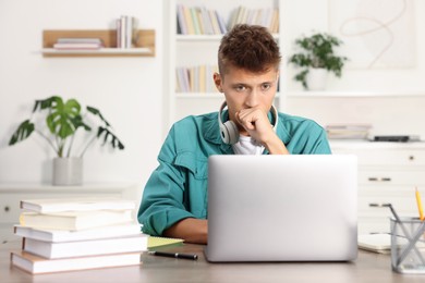 Student studying with laptop at table indoors