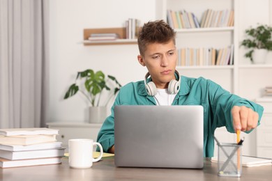 Photo of Student with headphones studying at table indoors