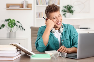 Photo of Student studying with laptop at table indoors