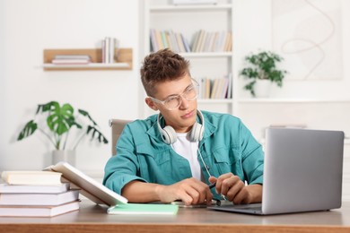 Student studying with laptop at table indoors