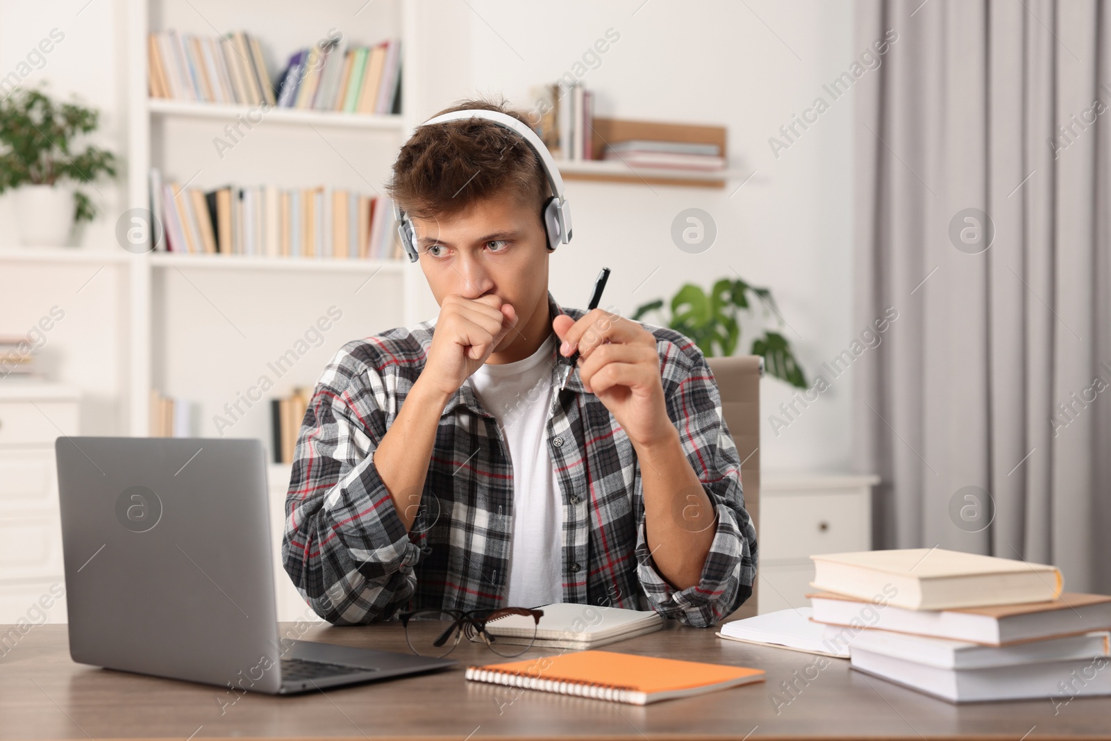 Photo of Student in headphones studying at table indoors