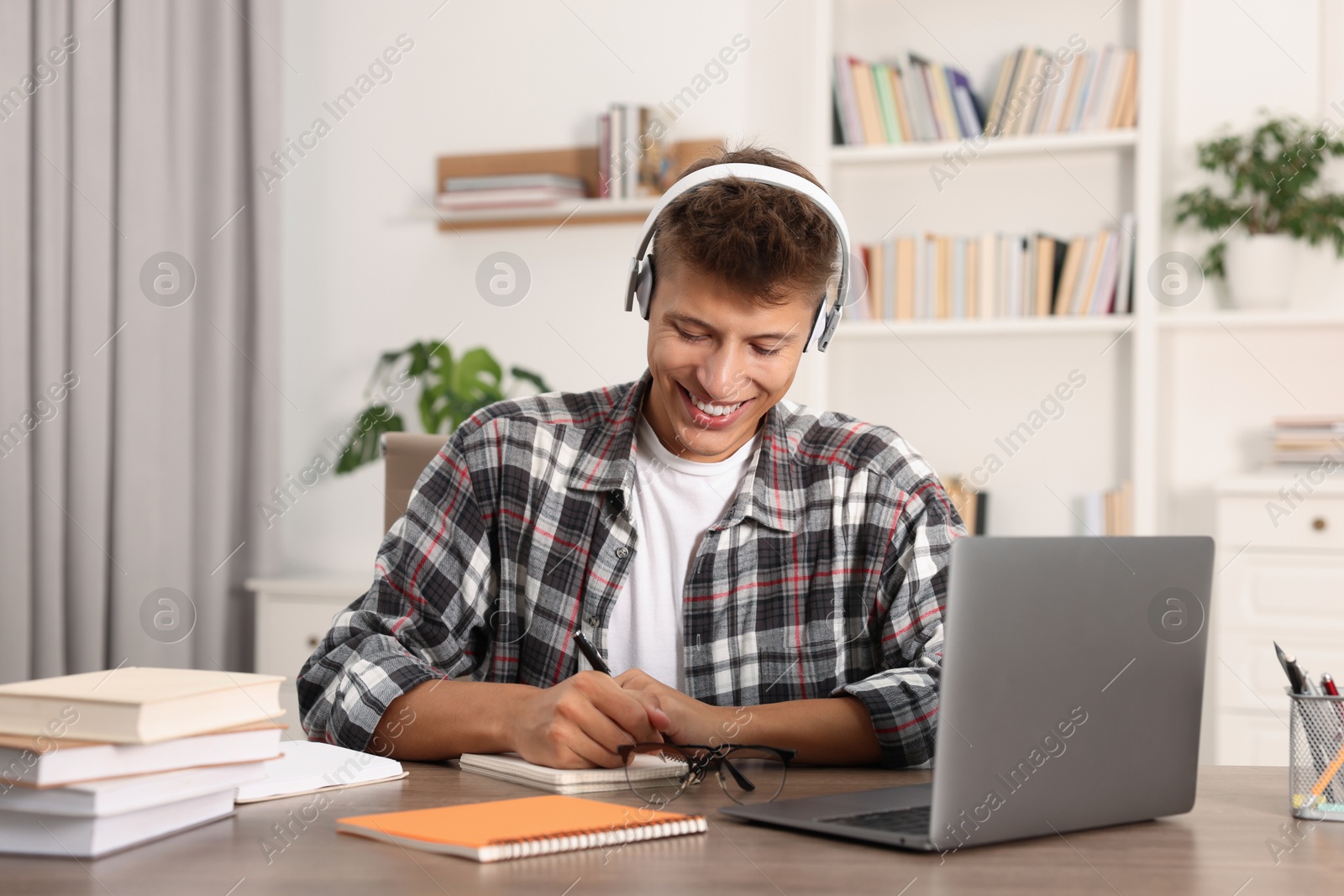 Photo of Student in headphones studying at table indoors