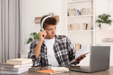 Student in headphones studying at table indoors