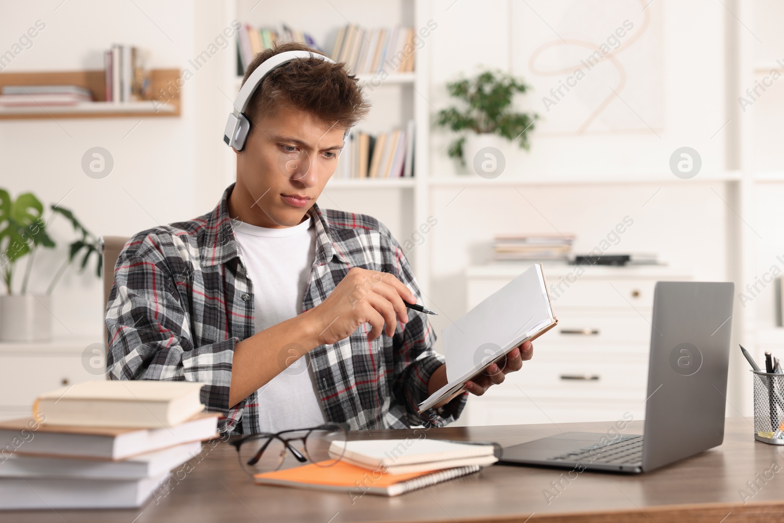 Photo of Student in headphones studying at table indoors