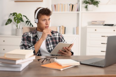 Photo of Student in headphones studying at table indoors