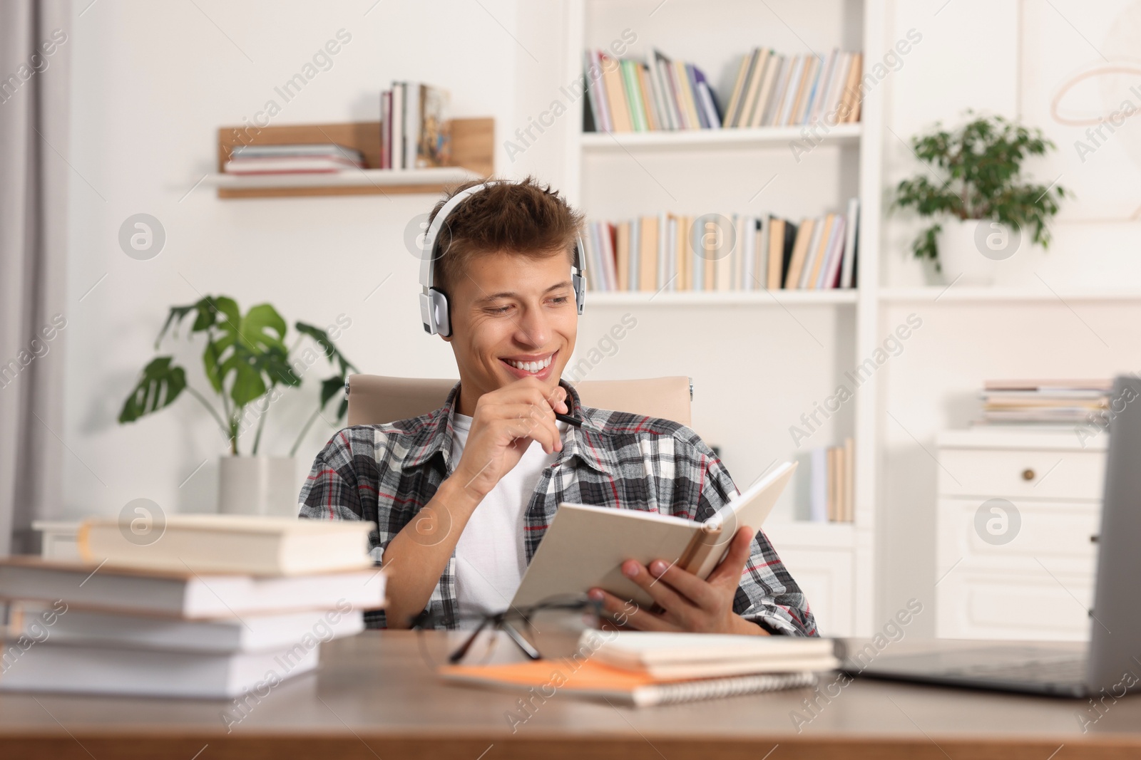 Photo of Student in headphones studying at table indoors