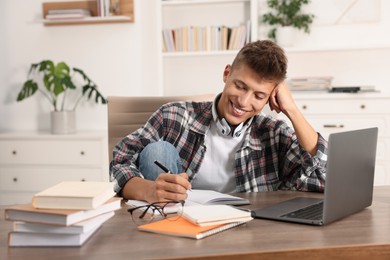 Photo of Student taking notes while studying at table indoors