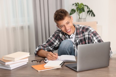 Student studying with laptop at table indoors