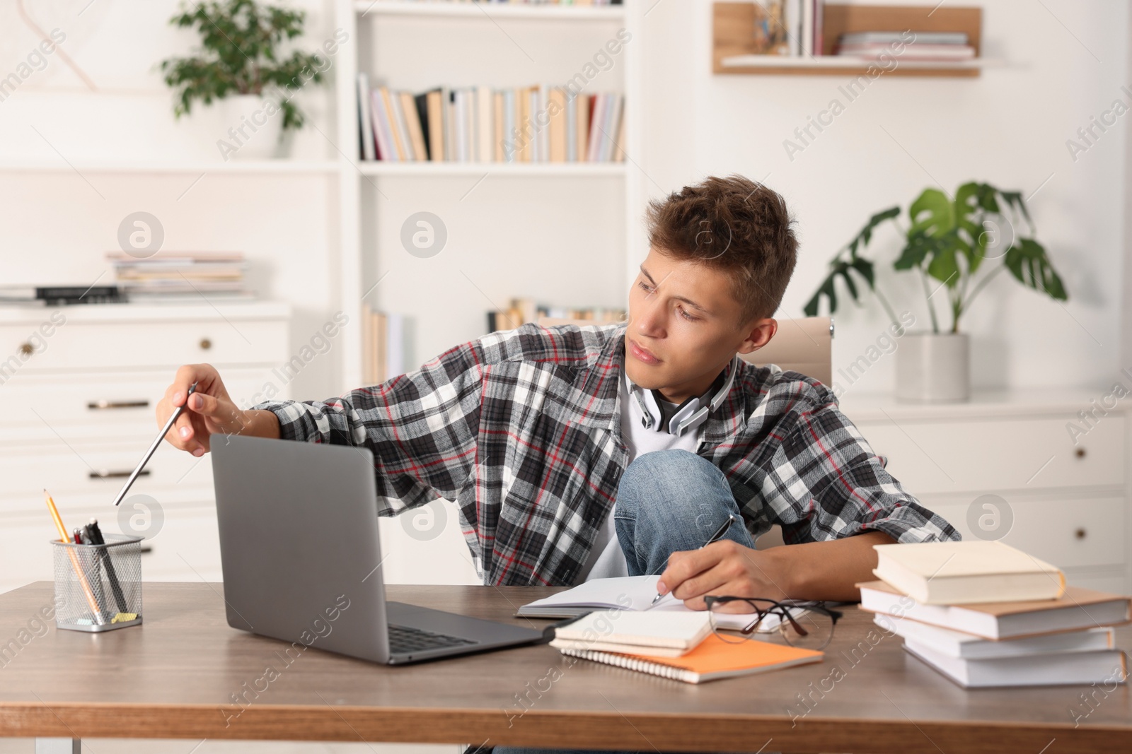 Photo of Student taking notes while studying at table indoors