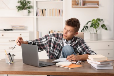 Student taking notes while studying at table indoors