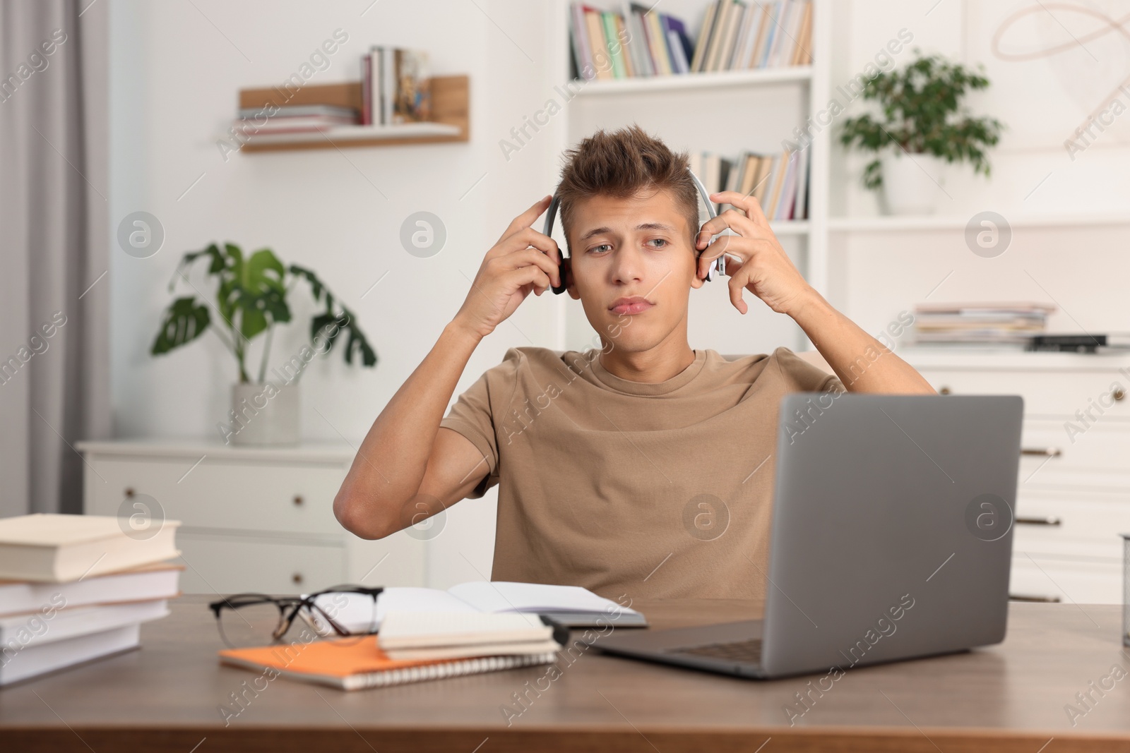 Photo of Student in headphones studying at table indoors