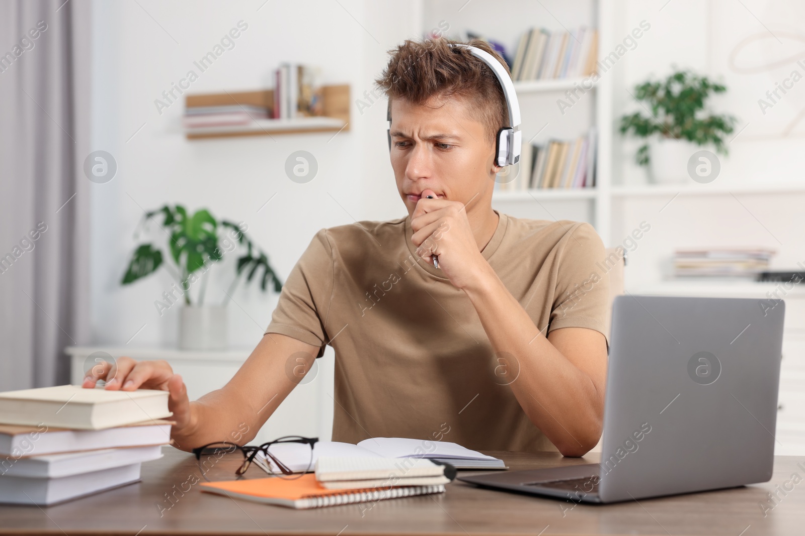 Photo of Student in headphones studying at table indoors