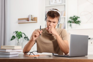 Photo of Student in headphones studying at table indoors