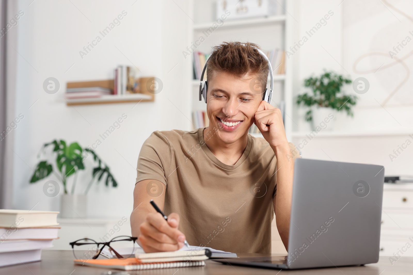 Photo of Student in headphones studying at table indoors