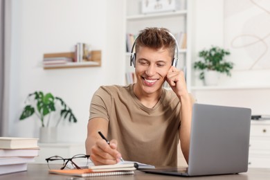 Photo of Student in headphones studying at table indoors