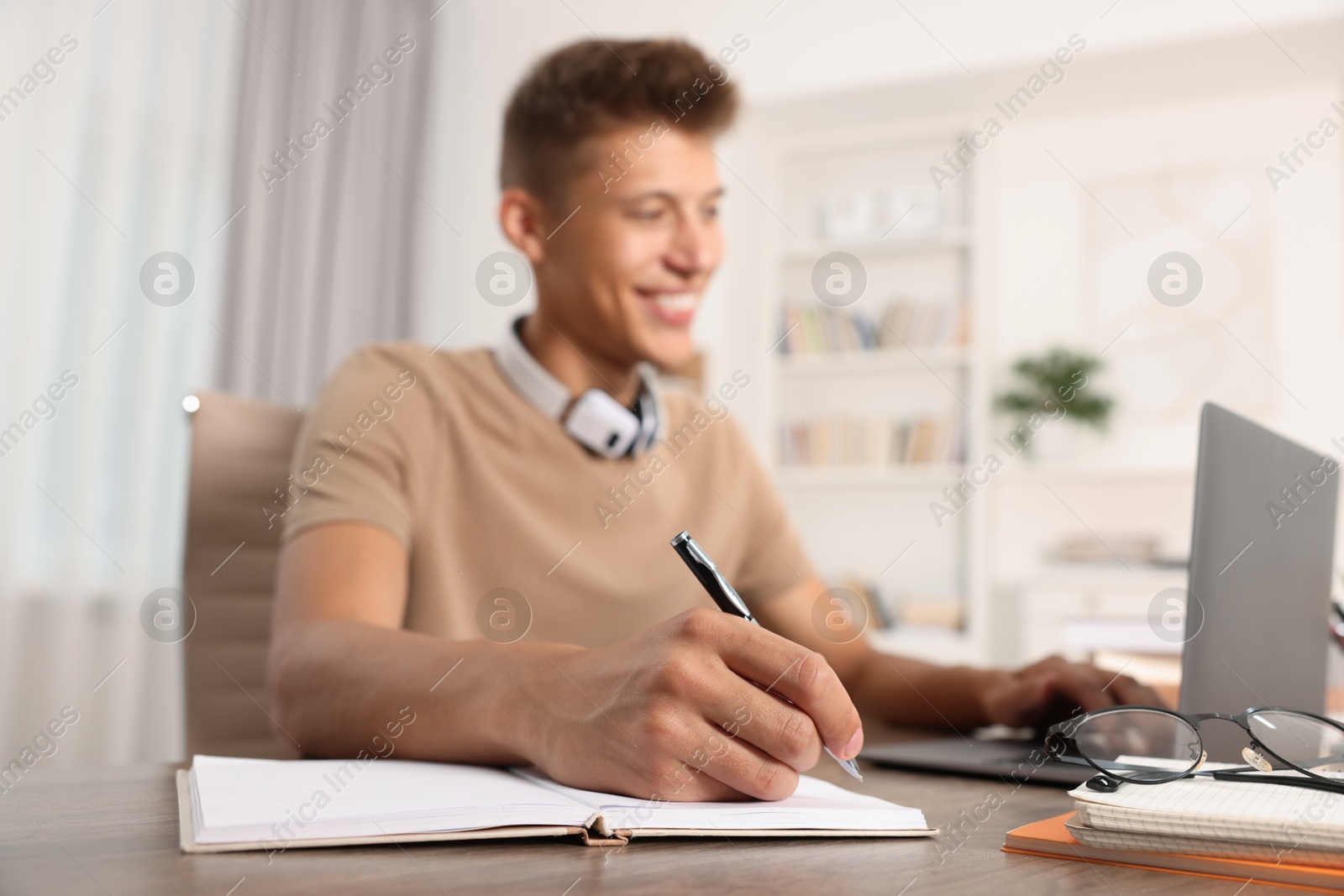 Photo of Student studying with laptop at table indoors, selective focus