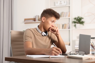 Student studying with laptop at table indoors