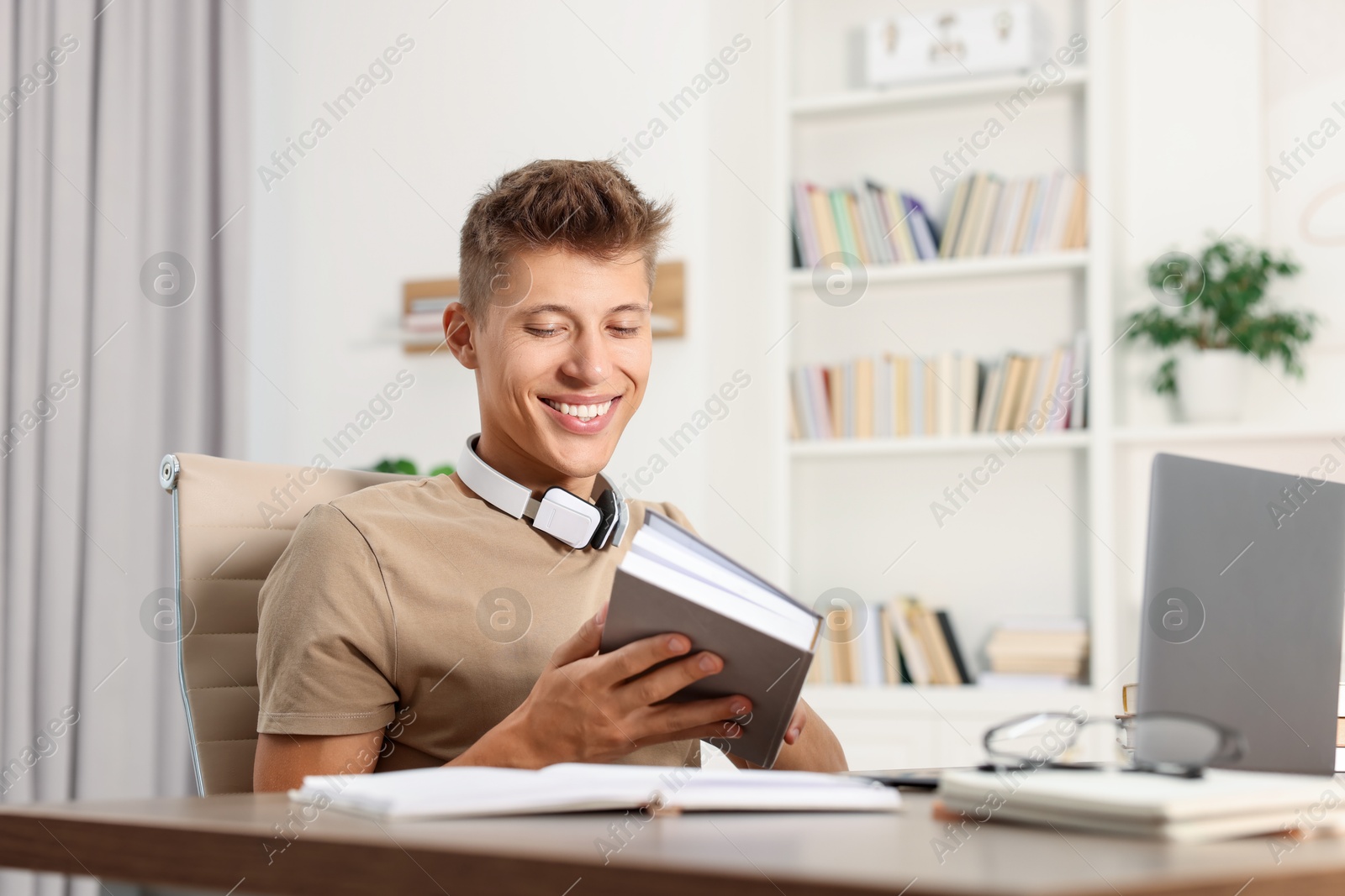 Photo of Student with book studying at table indoors