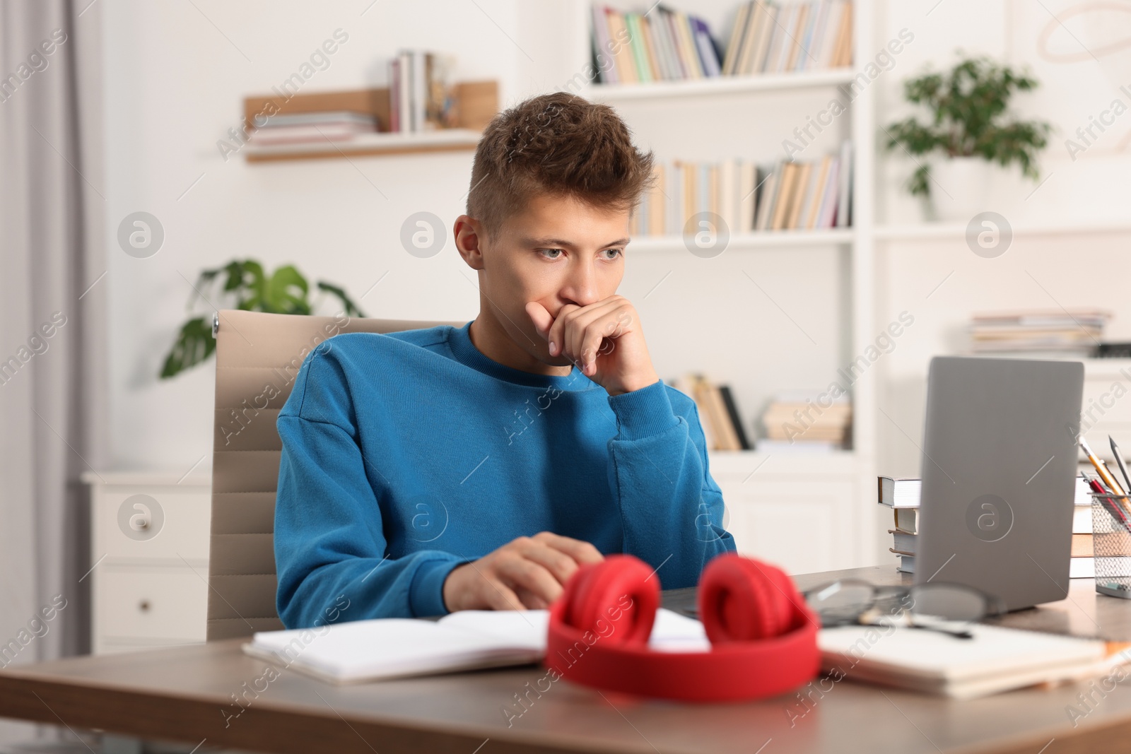 Photo of Student studying with laptop at table indoors