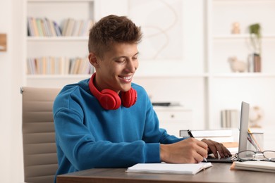 Student with headphones studying at table indoors