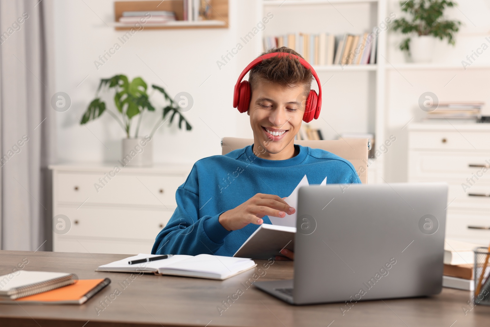 Photo of Student in headphones studying at table indoors