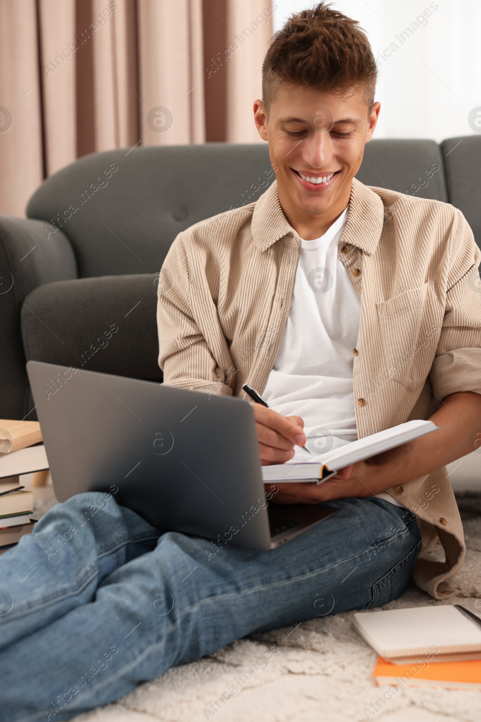 Photo of Student taking notes while studying on floor at home