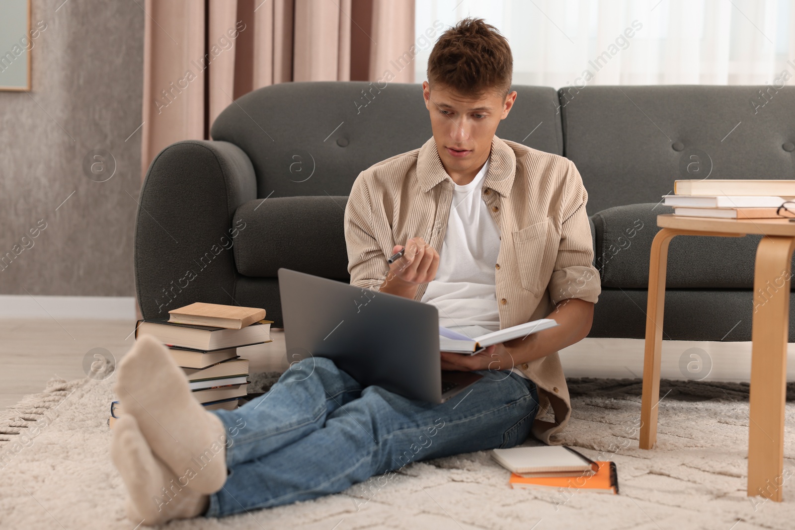 Photo of Student studying with laptop on floor at home