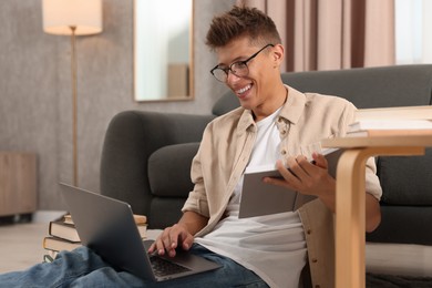 Student studying with laptop on floor at home