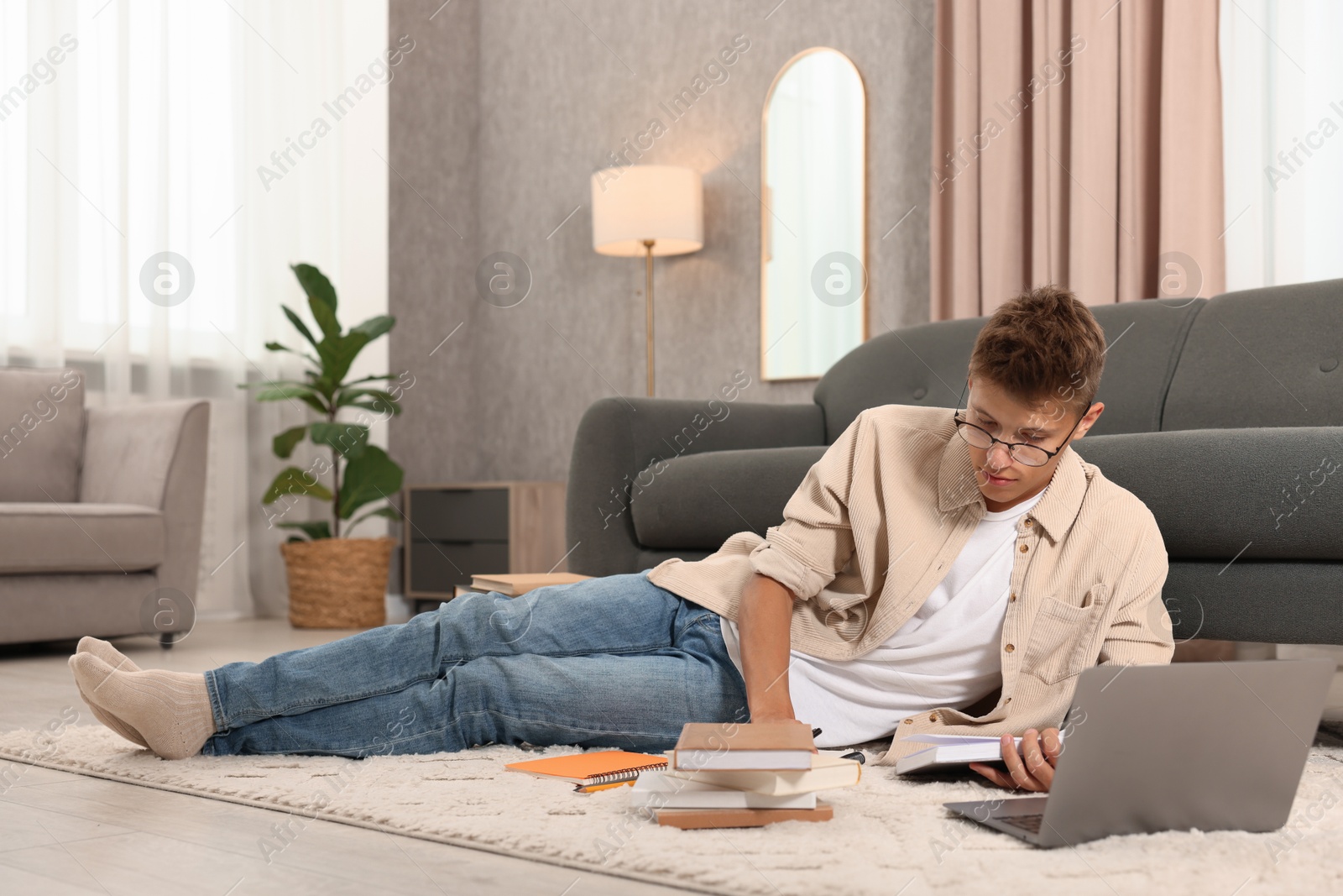 Photo of Student in glasses studying on floor at home