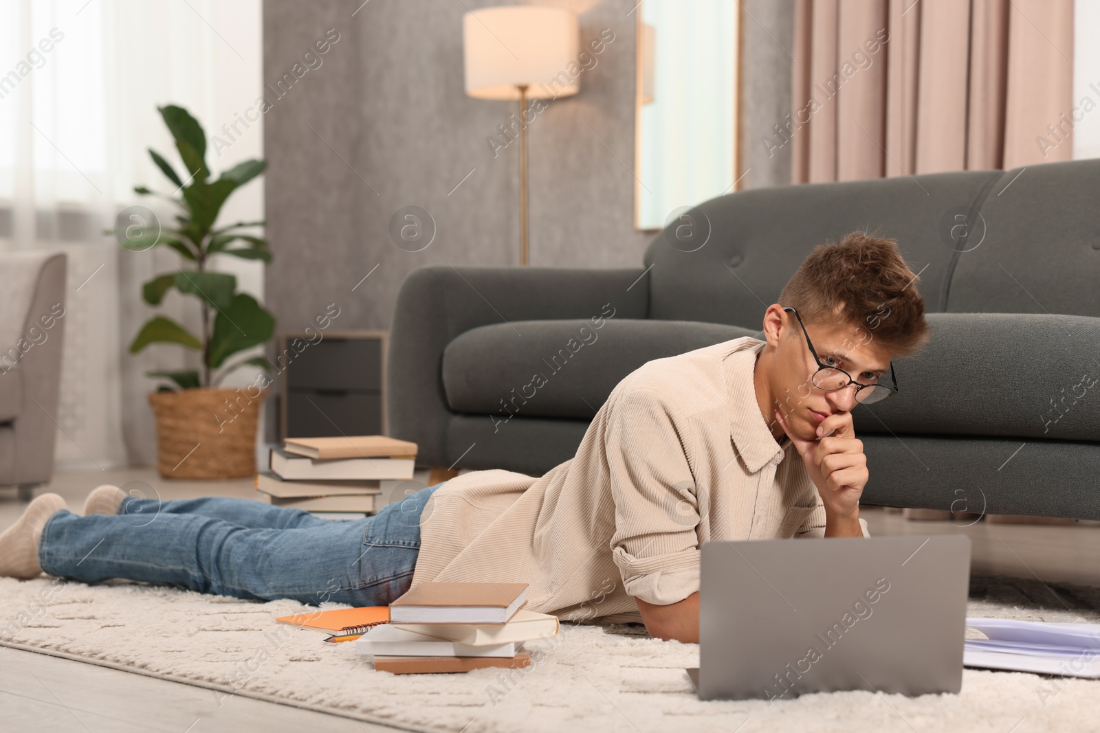 Photo of Student in glasses studying on floor at home