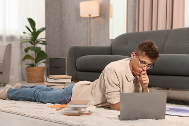 Student in glasses studying on floor at home