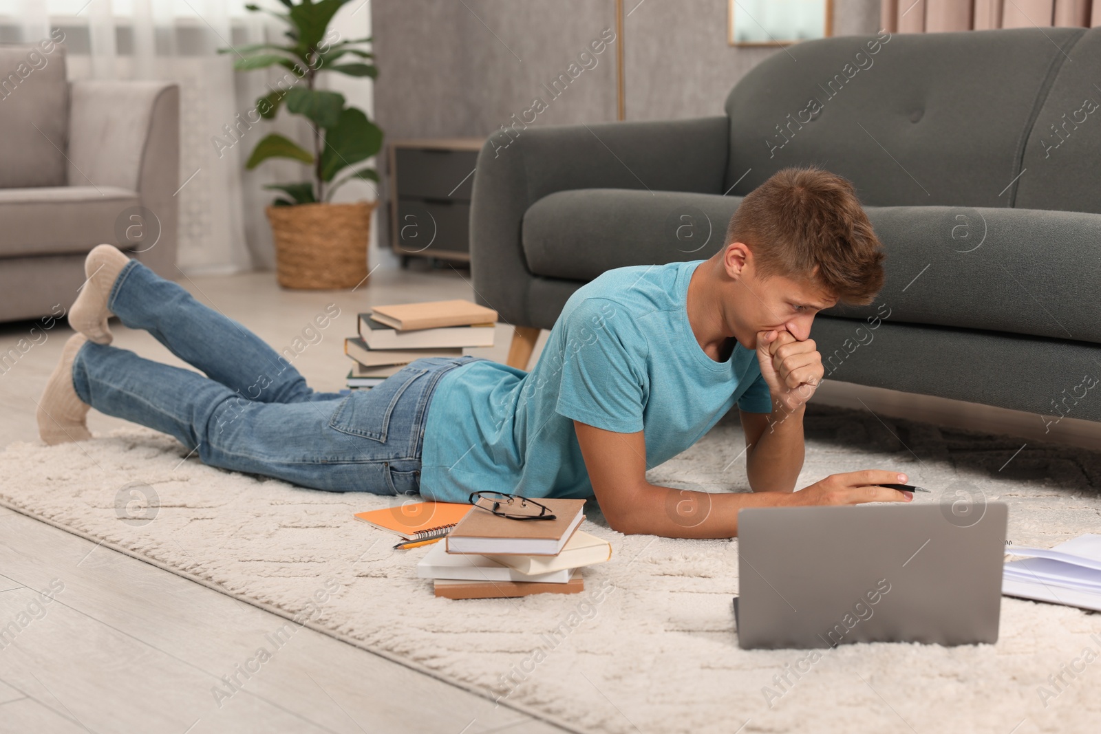 Photo of Student with books studying on floor at home