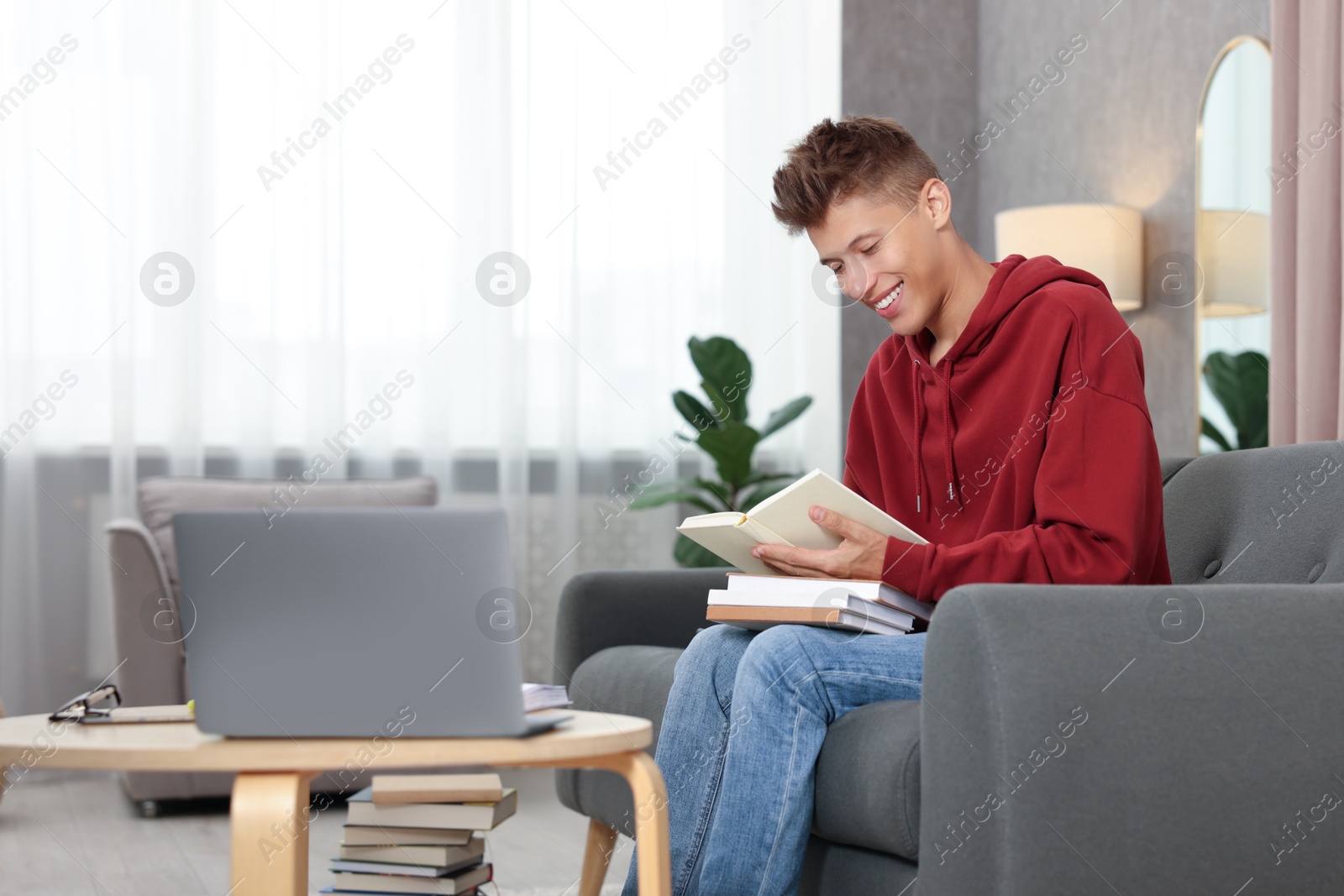 Photo of Student with books studying on sofa at home