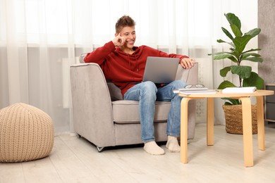 Photo of Student studying with laptop in armchair at home