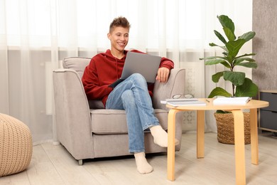 Photo of Student studying with laptop in armchair at home