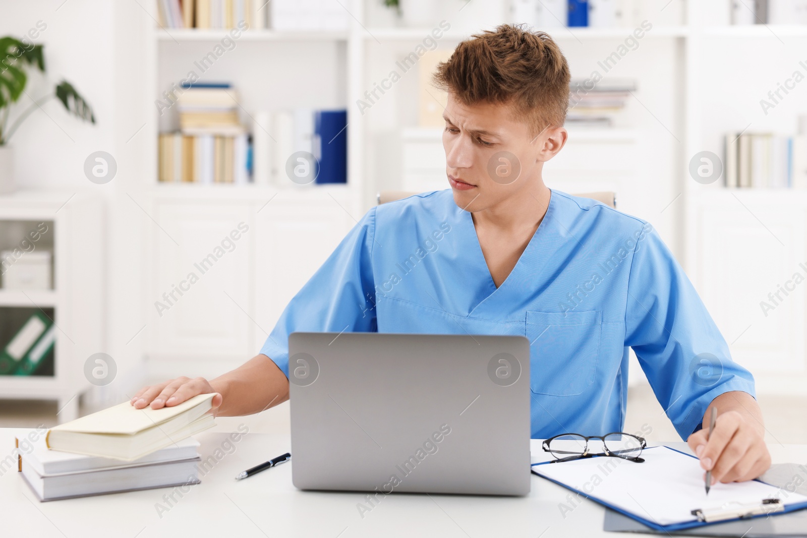 Photo of Medical student in uniform studying at table indoors