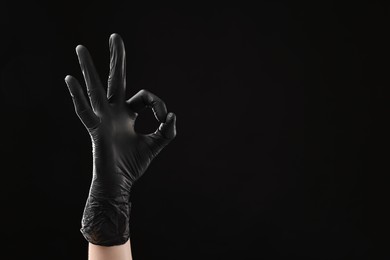 Photo of Man in latex glove showing OK gesture on black background, closeup. Space for text