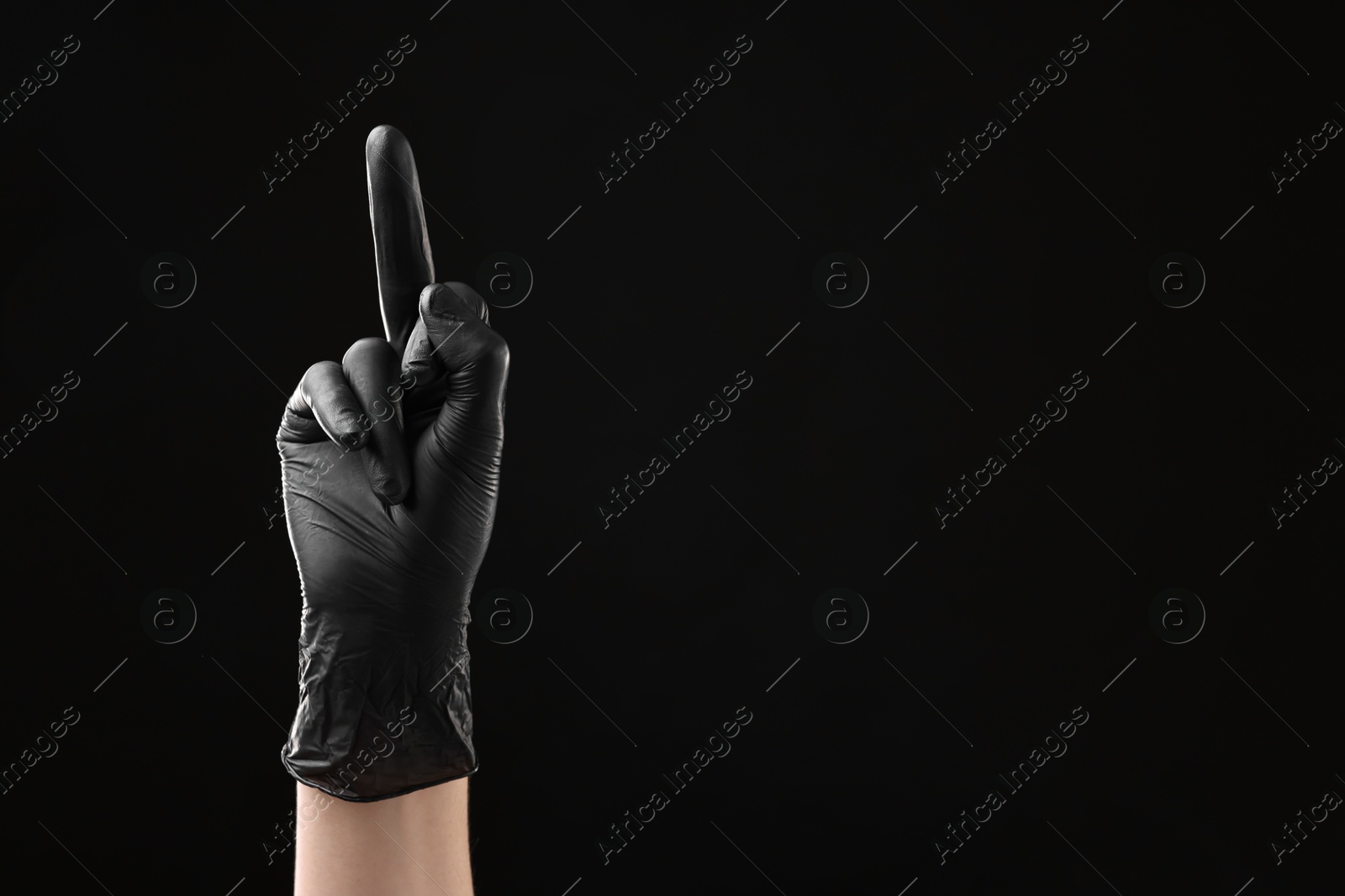 Photo of Man in latex glove showing middle finger on black background, closeup. Space for text