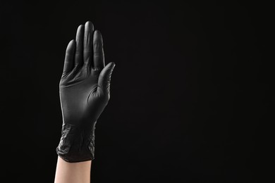 Photo of Man wearing latex glove on black background, closeup. Space for text