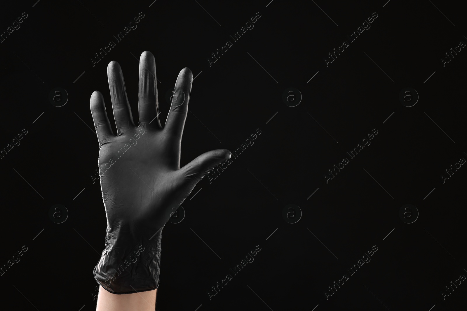 Photo of Man wearing latex glove on black background, closeup. Space for text