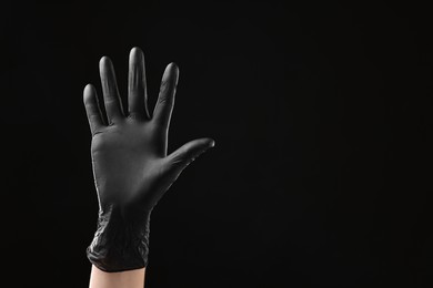 Photo of Man wearing latex glove on black background, closeup. Space for text