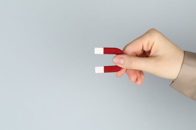 Photo of Woman with horseshoe magnet on grey background, closeup. Space for text