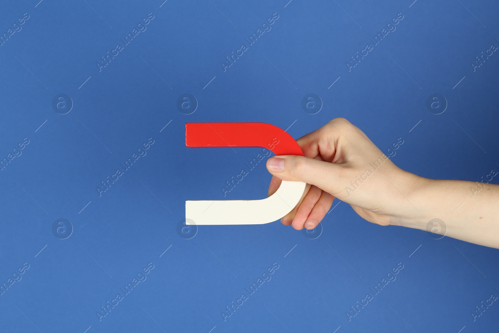 Photo of Woman with horseshoe magnet on blue background, closeup