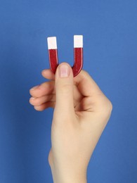 Photo of Woman with horseshoe magnet on blue background, closeup