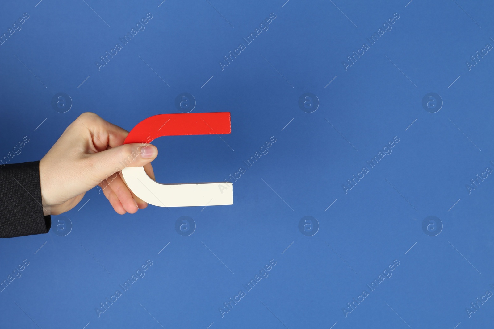 Photo of Woman with horseshoe magnet on blue background, closeup. Space for text