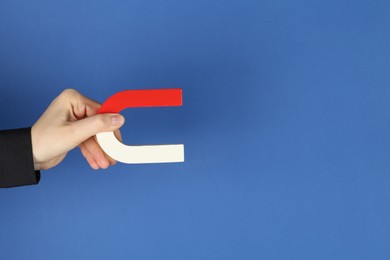 Photo of Woman with horseshoe magnet on blue background, closeup. Space for text