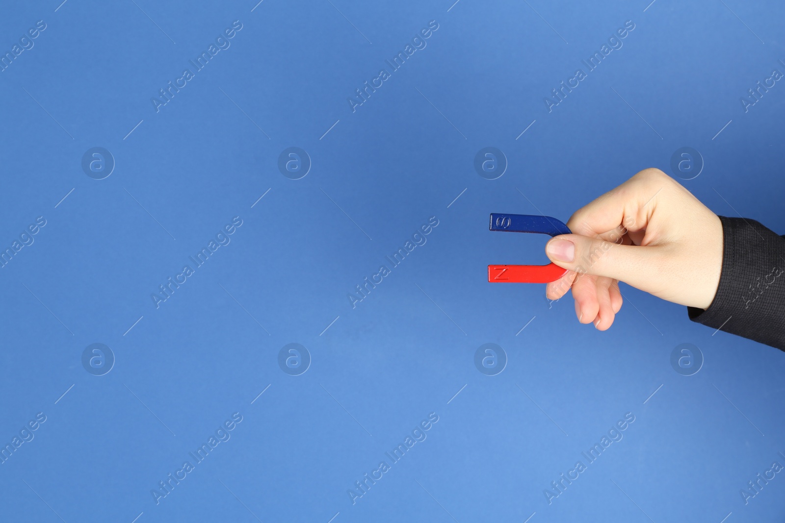 Photo of Woman with horseshoe magnet on blue background, closeup. Space for text